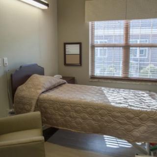 A hospital room with a single bed and large window.