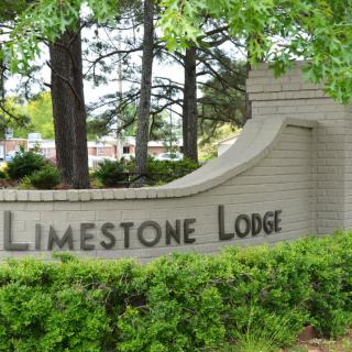 Entrance sign for Limestone Lodge surrounded by trees and greenery.