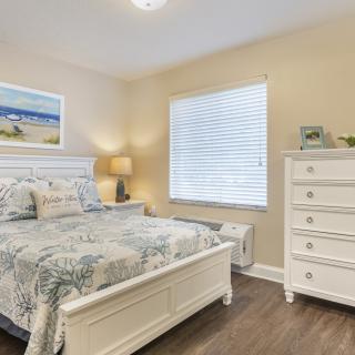 A cozy bedroom with white furniture and floral bedding.