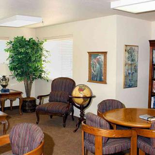 A cozy office interior with a meeting area, featuring round tables, chairs, a globe, and artwork on the walls.