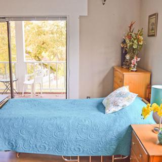 A cozy bedroom with a single bed and a view of the balcony.