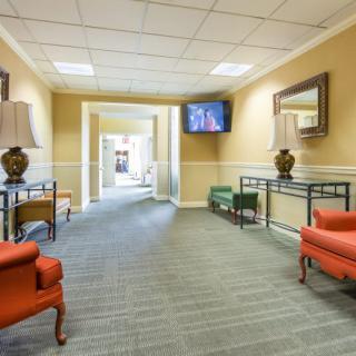 A comfortable waiting area with orange chairs and a television mounted on the wall.