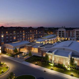 A well-lit hotel building at dusk with an illuminated exterior and scenic skyline.