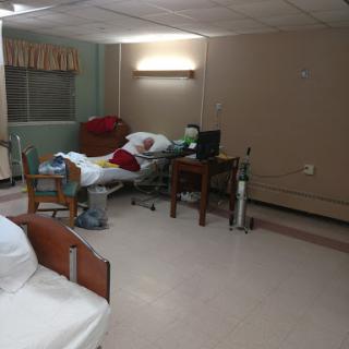 A view of a hospital patient room with an unoccupied bed and medical equipment.