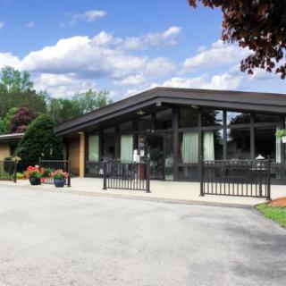 A modern funeral home building with a well-maintained driveway and surrounding greenery.