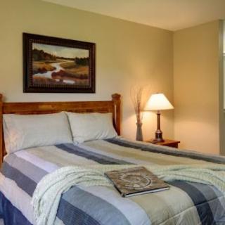 A cozy bedroom featuring a neatly made bed, a bedside lamp, and decorative artwork on the wall.