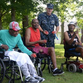 A group of people, including a person in military uniform, enjoying time together outdoors in wheelchairs.