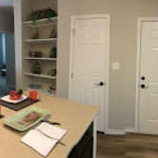 A modern kitchen interior with shelves, countertop items, and two doors.