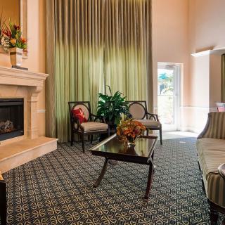 A cozy living room with elegant furniture, a fireplace, and large curtains.