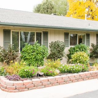 A charming house with a well-maintained front garden featuring lush greenery and colorful flowers.