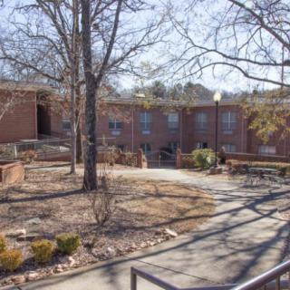 A brick building surrounded by bare trees and pathways on a clear winter day.