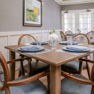 A beautifully set dining table with elegant place settings in a bright, well-lit dining room.