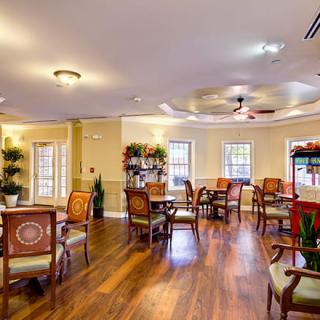 A spacious dining area with wooden floors and elegant seating arrangements.