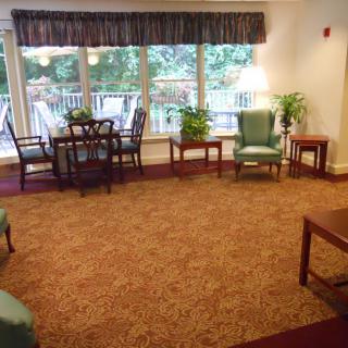 A cozy living room with ample seating, large windows, plants, and a dining table.