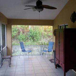 A cozy screened patio with chairs and a ceiling fan overlooking nature.
