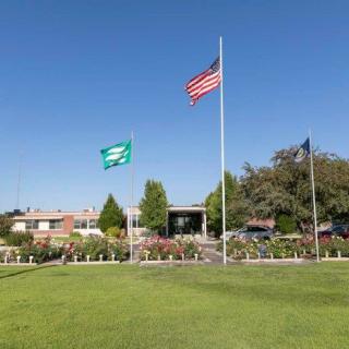 A building with flags flying in front on a sunny day.