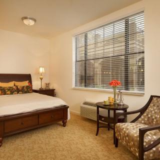A cozy bedroom with a comfortable bed, stylish chair, and bright window.