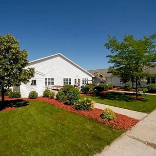 A picturesque suburban house with a well-maintained lawn and garden under a clear blue sky.