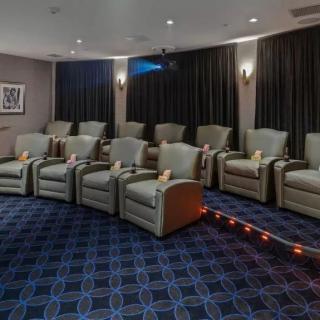 A cozy home theater room with rows of plush recliners and a large projection screen.