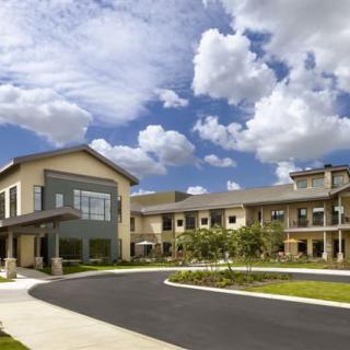 A modern building with a curved driveway under a partly cloudy sky.