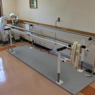 A set of parallel bars used for physical therapy and rehabilitation exercises in an indoor facility.