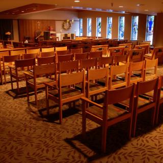 Interior view of a chapel with wooden chairs and natural lighting.