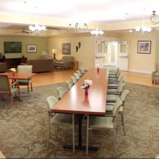 A spacious interior with a long conference table and chairs, adjacent to a cozy living room area.