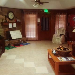 A cozy living room with a coffee table, chair, and wall clock.