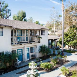 A sunny view of a two-story apartment building with balconies and a landscaped garden.
