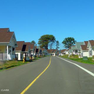 A peaceful suburban street lined with houses under a clear blue sky.