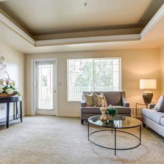 A bright and elegantly decorated living room with comfortable sofas, a glass coffee table, and modern lighting.