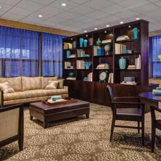 A cozy lounge area with a large bookshelf, sofa, and table.