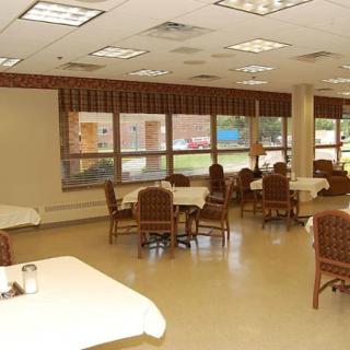 An empty dining area with neatly arranged tables and chairs, featuring large windows that let in natural light.