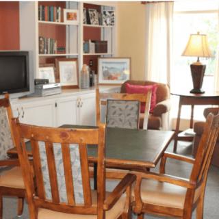 A cozy living room with a table and chairs, bookshelves, and a lamp.
