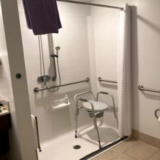 An accessible shower setup featuring grab bars and a shower chair for safety and convenience.