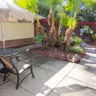 A sunny patio area with outdoor seating and palm trees.