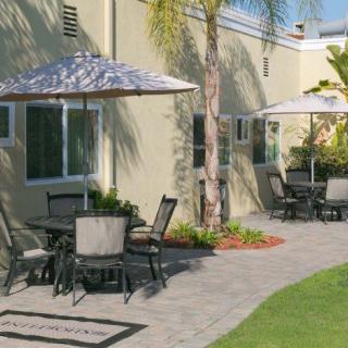 An outdoor patio area with tables, chairs, and umbrellas near a building.