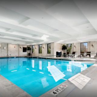 An inviting indoor swimming pool with seating areas and bright lighting.