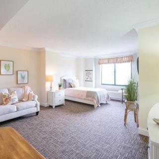 A bright and comfortable interior featuring a cozy living space with a bed, sofa, and window.