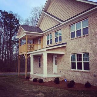 A modern two-story brick house with a front porch and upper balcony.