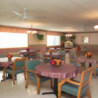 A cozy dining room with neatly arranged tables and chairs, adorned with decorative flowers.