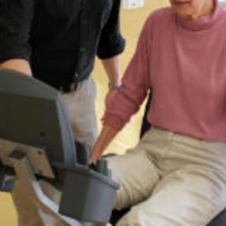 A senior person engaged in a physical therapy session with assistance.