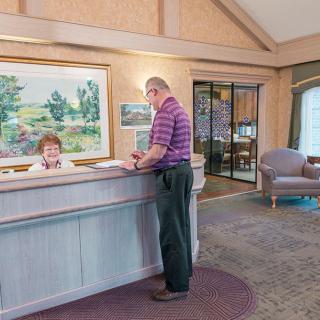A man interacting with a receptionist at an office desk.