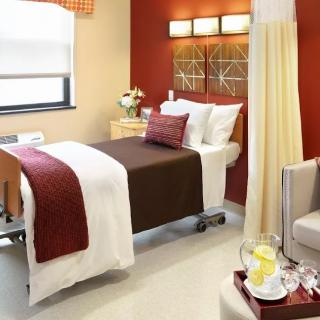 A well-decorated hospital room featuring a comfortable bed, warm lighting, and stylish decor.