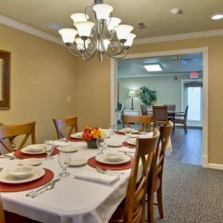 A neatly arranged dining room with a large table set for dinner under a chandelier.