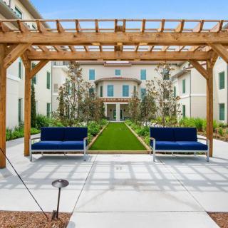 A beautifully landscaped garden with a pergola and benches, leading to a building facade.