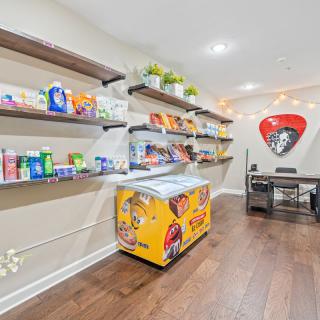 A small store with shelves stocked with various snacks and products, featuring an ice cream freezer and a neat wooden floor.