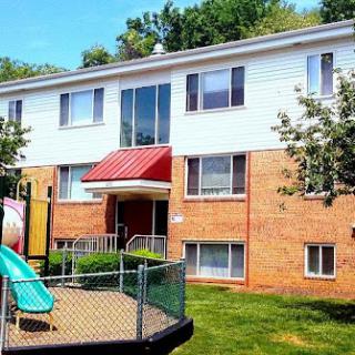 A view of a residential apartment building featuring a children's playground in the foreground.
