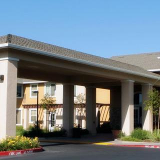 A residential building with a covered entrance and landscaped surroundings on a clear day.