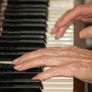 Hands playing piano keys.